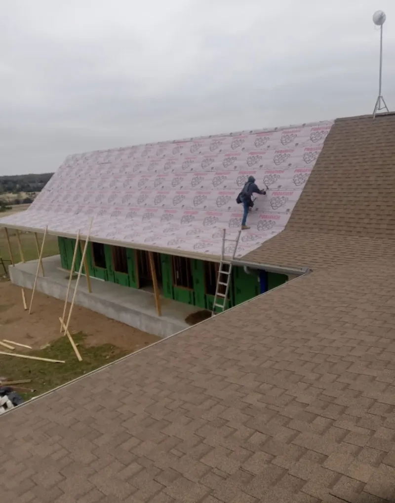 Worker preparing underlayment for a metal roof installation in Petoskey